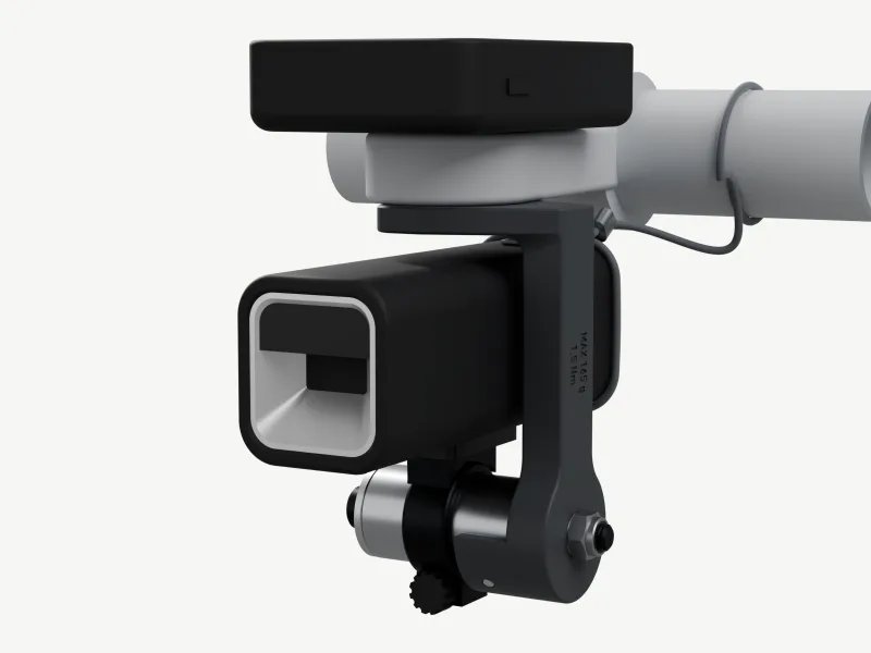 Render from front-left, just above: a black computer on a grey aluminium out-front, and under it the charcoal J-arm, MAX 165 g · 1.5 Nm on its side. The arm runs down beside a black lamp to a short silver aluminium stub under the lamp; the lamp's own dark bar band clamps round the stub and holds it upright, reflector forward. A grey cord runs from the bar to the lamp's rear.